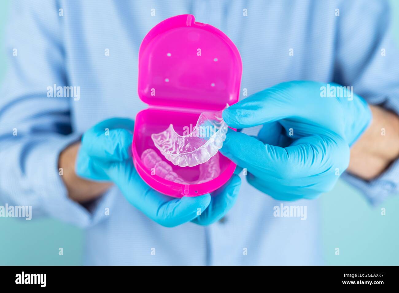 Dentist in gloves and blue shirt showing a dental splint in a pink ...