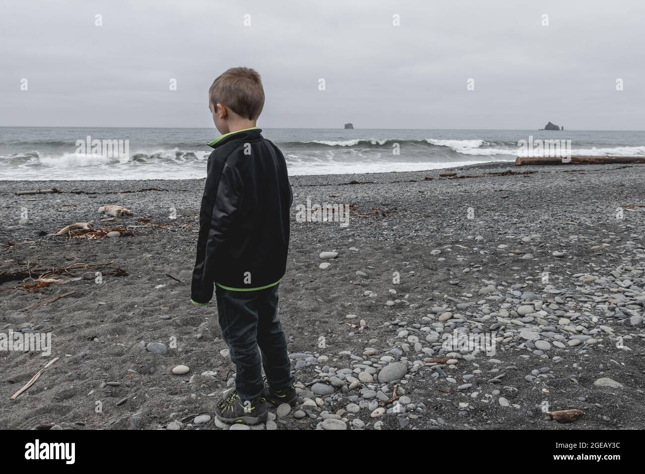 Young boy looking out at the waves on Rialto Beach in Olympic National Park. Stock Photo