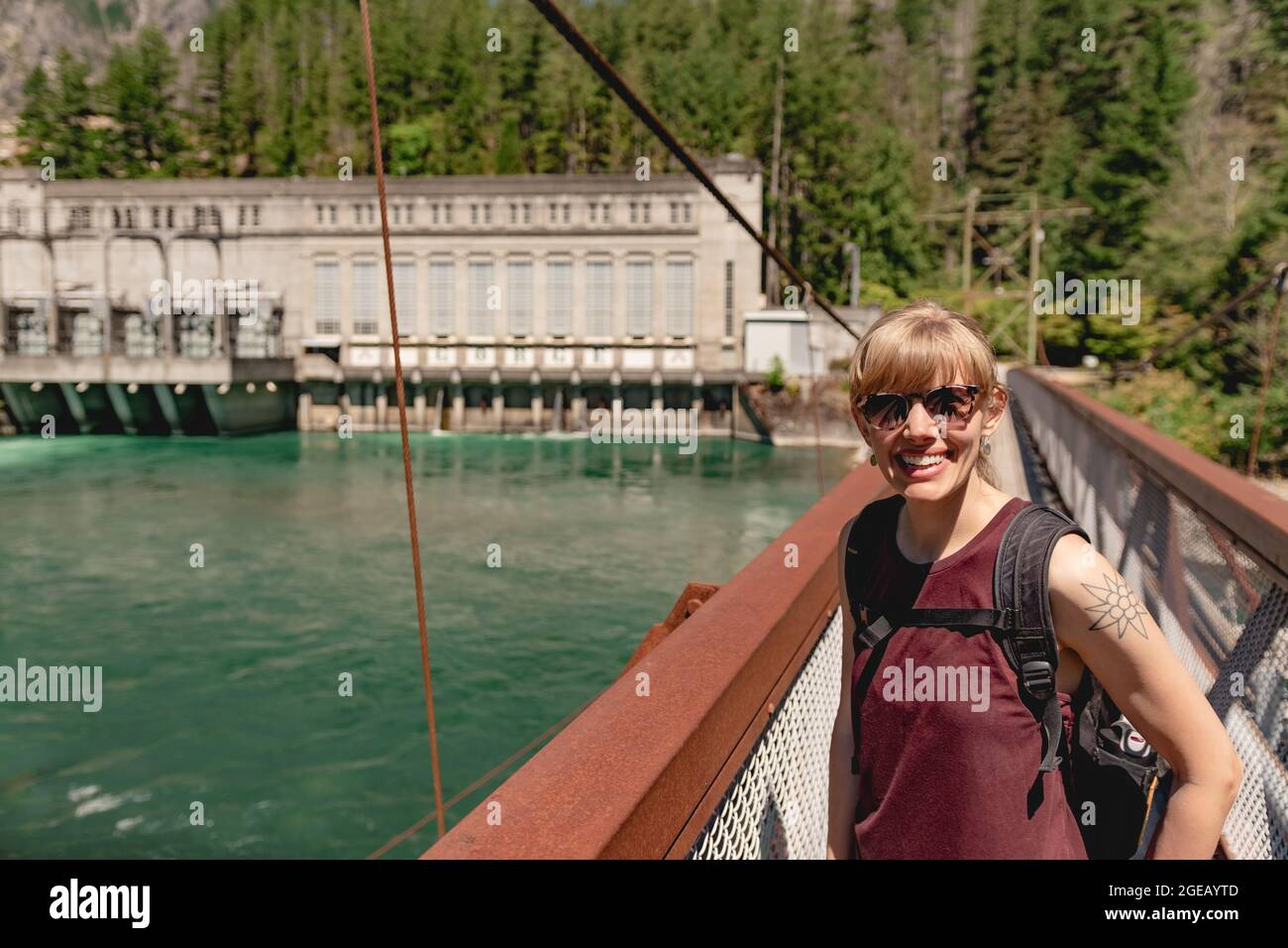 Woman smiling on a suspension bridge spanning the Skagit river in North Cascades National Park. Stock Photo