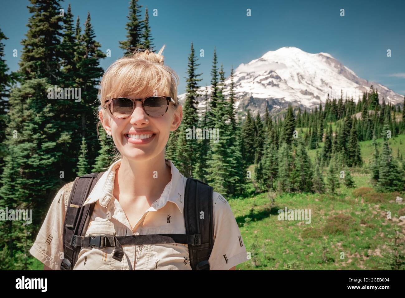 Young woman smiling in front of Mt Rainier on the Naches Peak Loop Trail in Mt. Rainier National Park. Stock Photo
