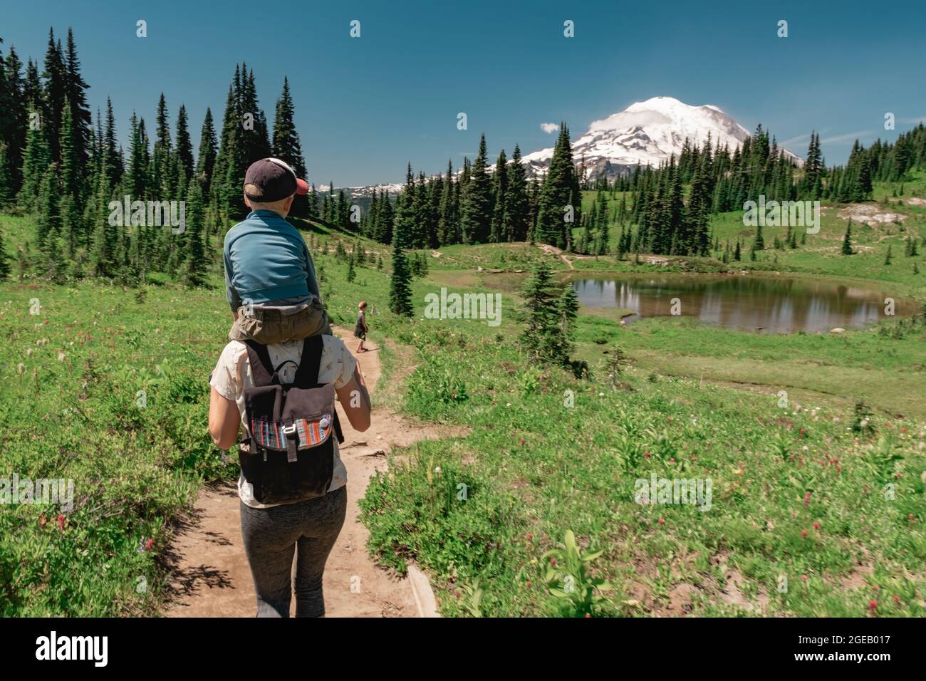 Young mother carrying son toward Mt Rainier on the Naches Peak Loop Trail in Mt. Rainier National Park. Stock Photo
