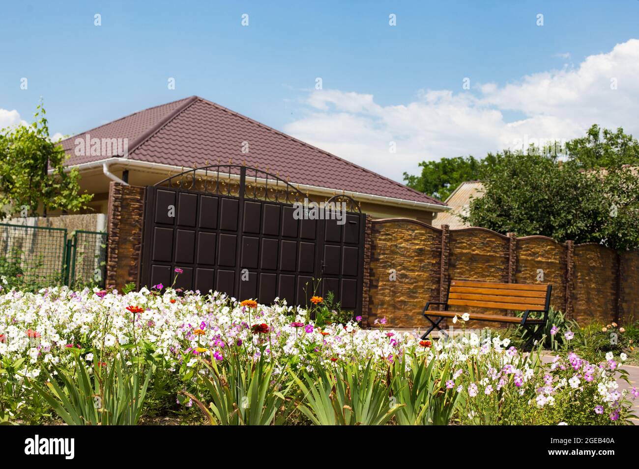 Beautiful house fenced around and with nice flowering garden on a front. Stock Photo