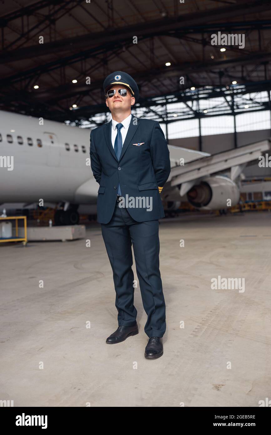 Full length shot of proud pilot in uniform and aviator sunglasses