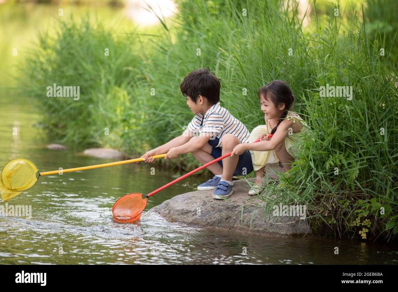 Chinese children playing with fishing net by the river Stock Photo