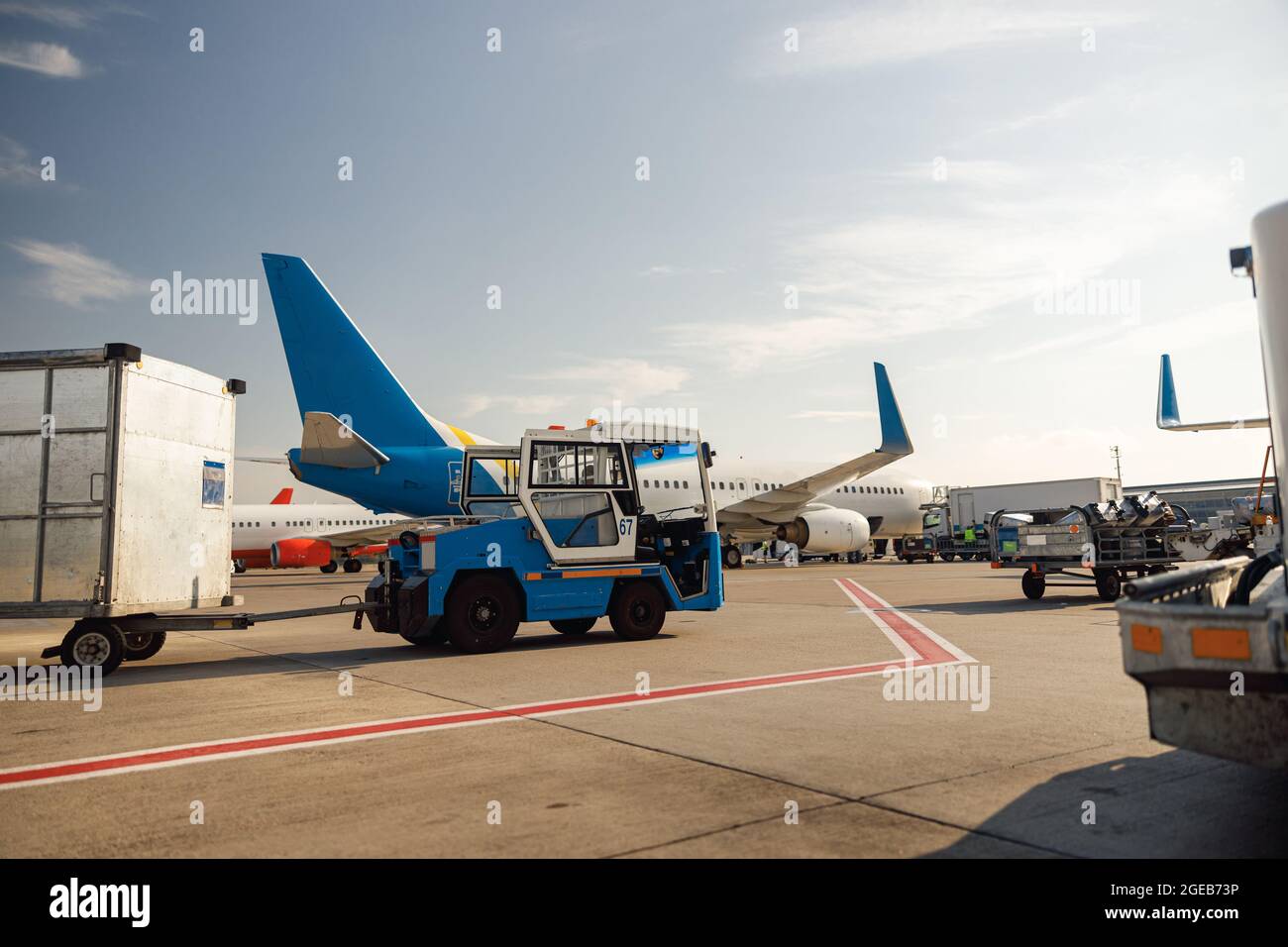 Airfield tractor near big modern airplane. Preparation of aircraft in airport hub on a daytime Stock Photo