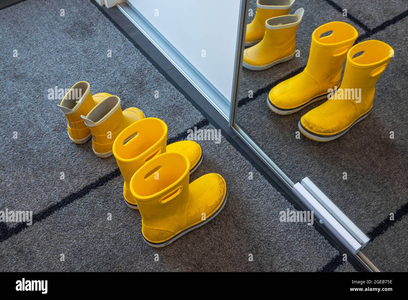 https://c8.alamy.com/comp/2GEB75E/close-up-view-of-yellow-childrens-rubber-boots-on-a-mat-near-a-cabinet-with-a-mirror-in-hallway-childrens-shoes-concept-sweden-2GEB75E.jpg