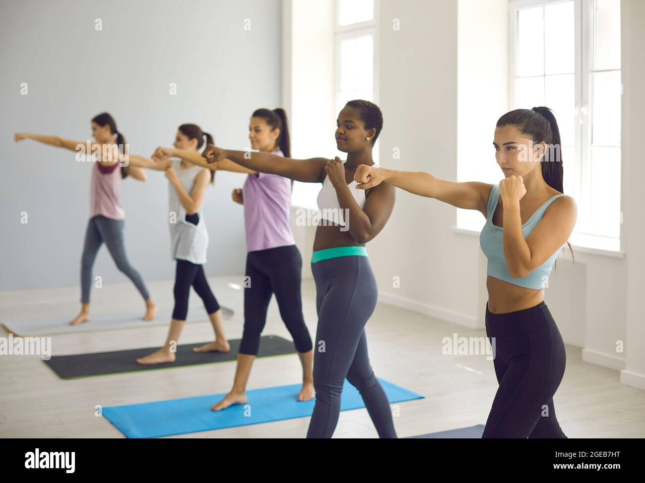 Diverse group of young women doing physical exercise during fitness workout at gym Stock Photo