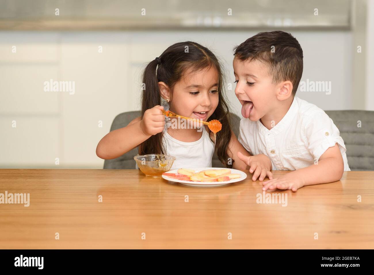 Little Funny Girl And Boy Eating Apple With Honey. Healthy Eating For