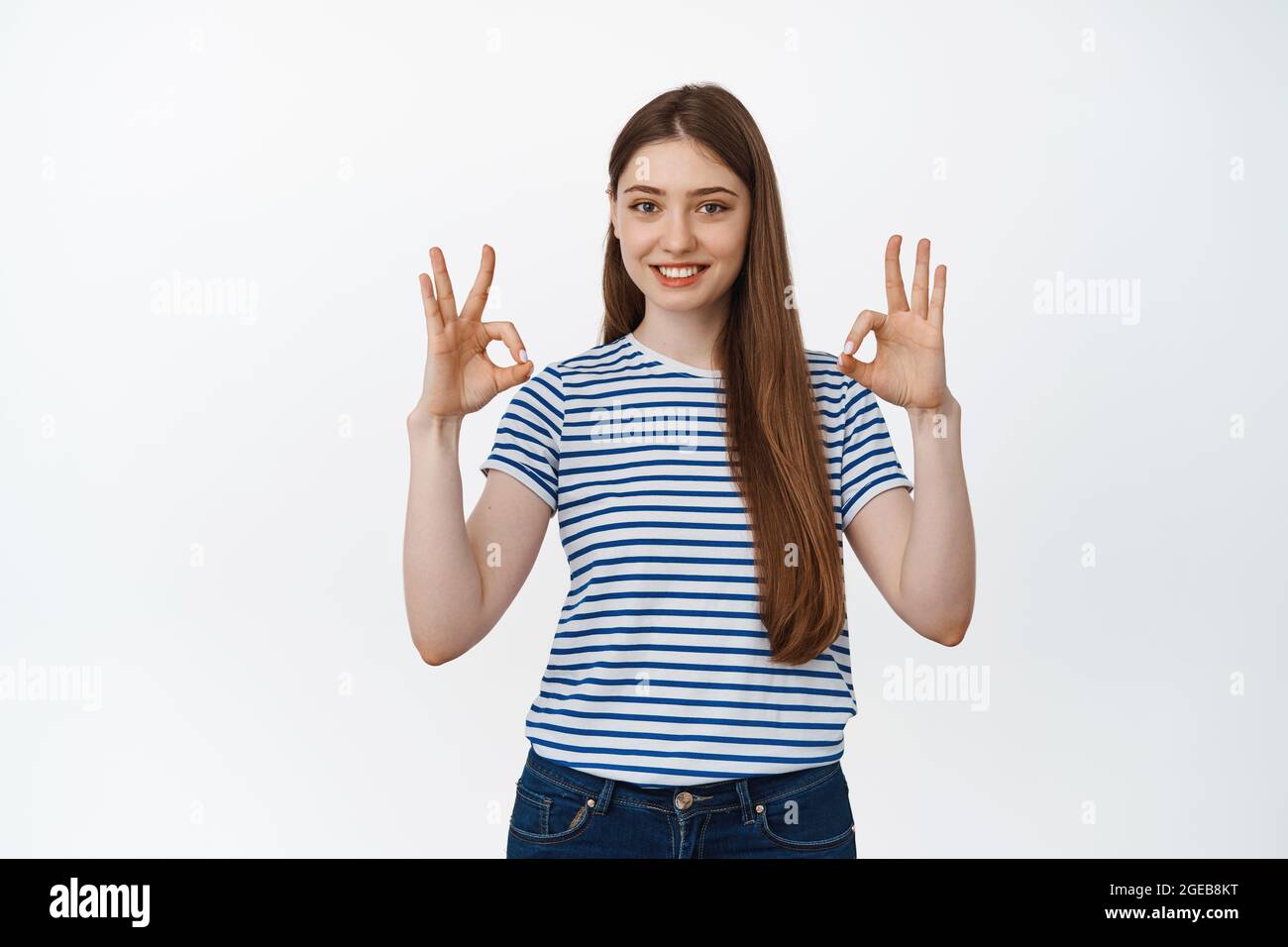 Smiling girl shows okay signs in approval, stands over white background ...