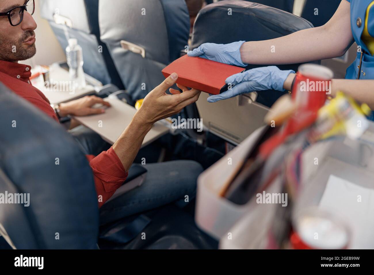 Close up shot of hands of male passenger getting lunch box from female flight attendant serving food on board Stock Photo