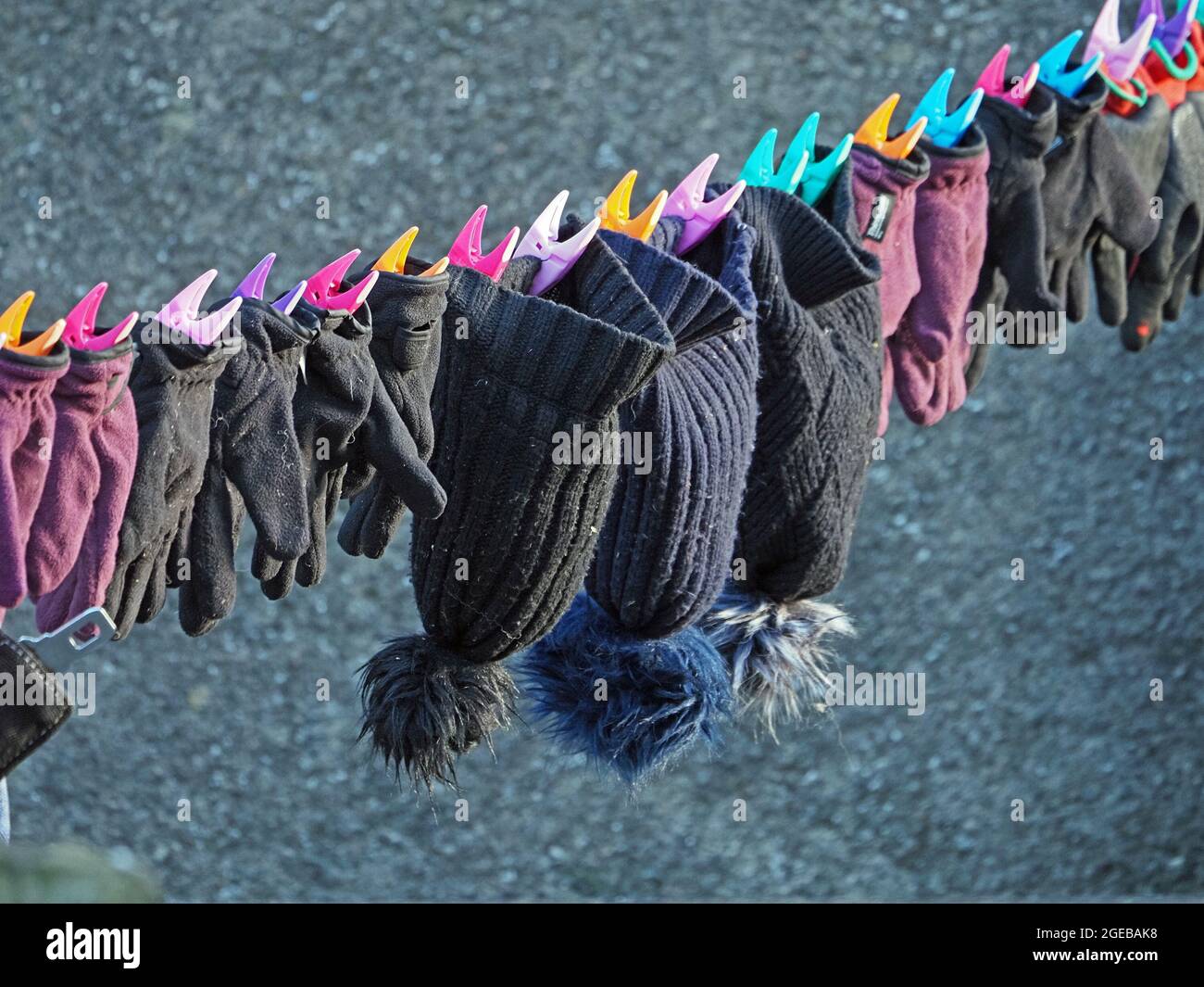 Bright sunshine on washing line with hats and gloves and colourful clothes-pegs on a farm in the Eden Valley Cumbria, England,UK Stock Photo