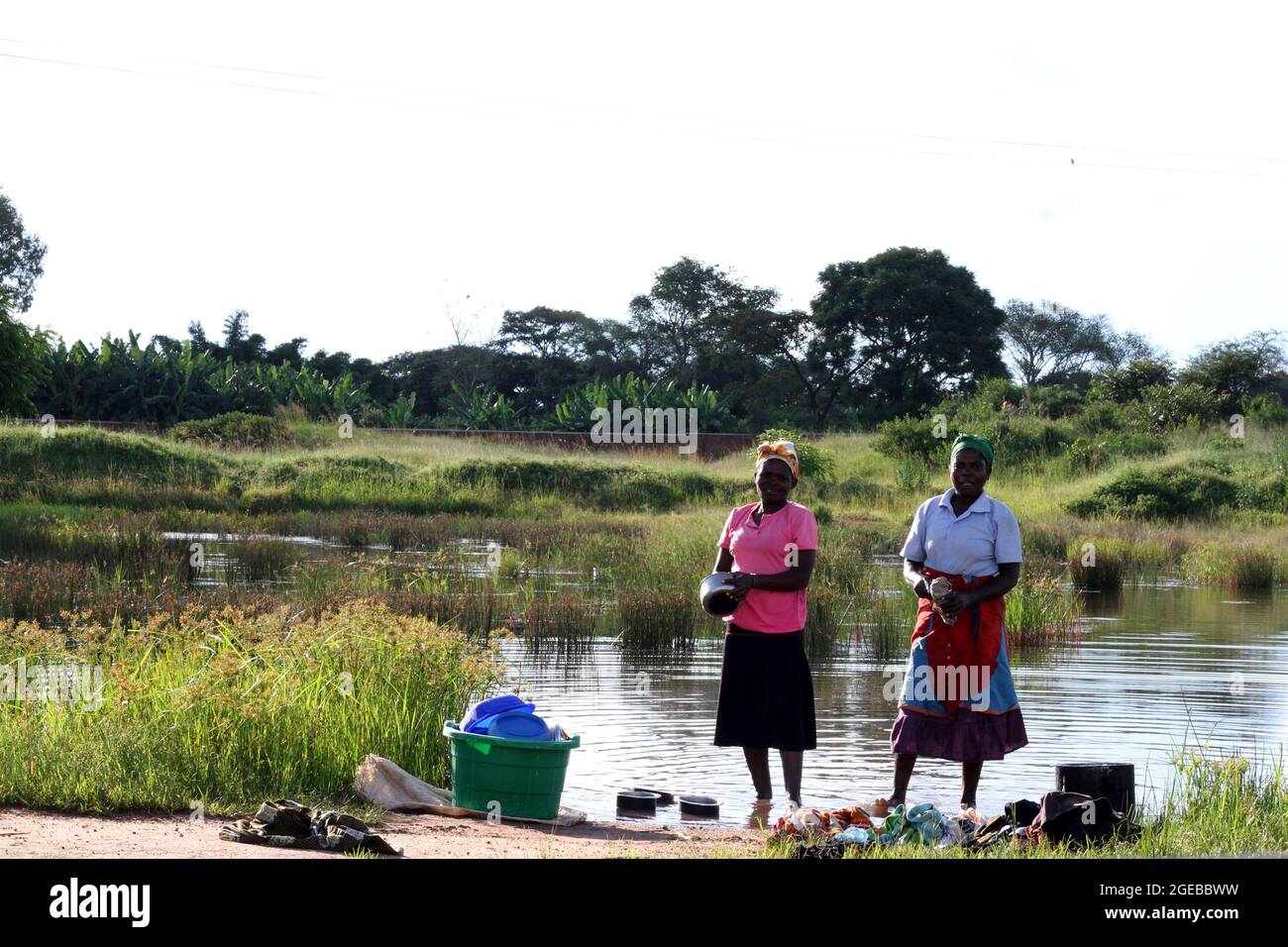 Two women are seen washing dishes at a river in Mchinji. Many people use open water sources. Mchinji, Malawi. Stock Photo