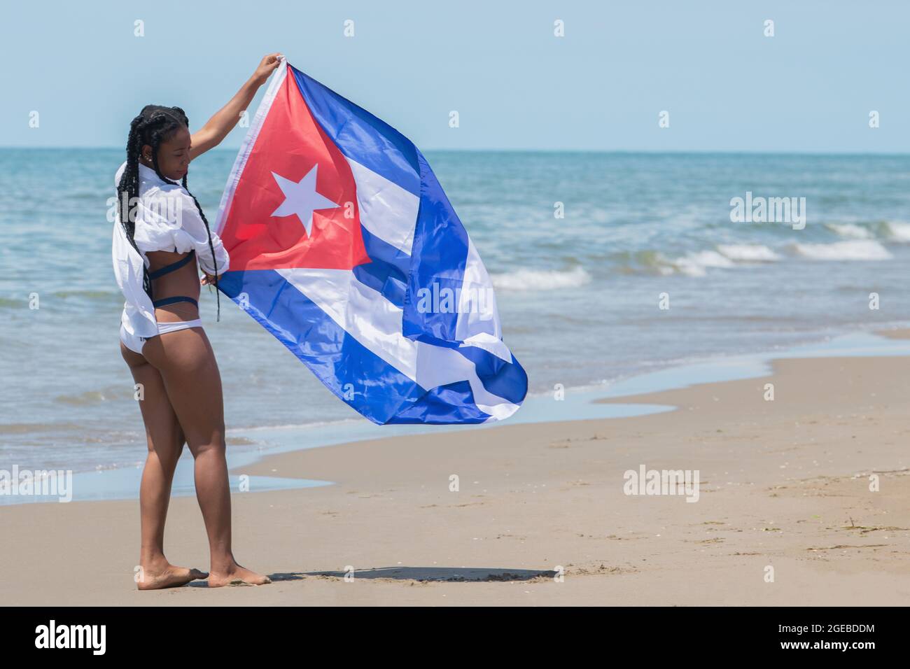 Young woman holding a Cuban flag on the beach Stock Photo - Alamy