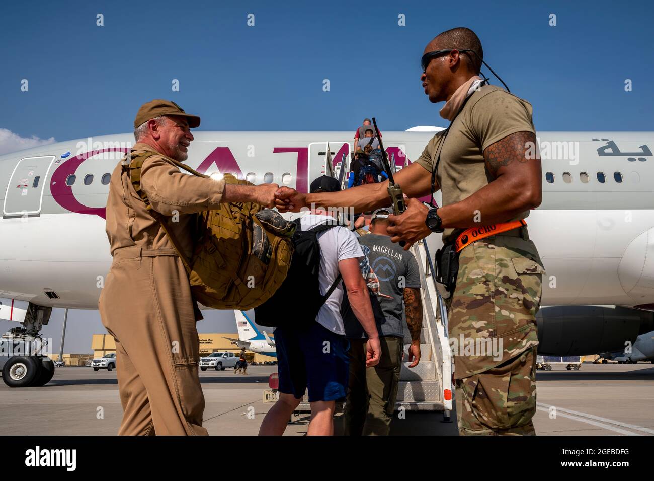 A member of the 8th Expeditionary Air Mobility Squadron assists U.S. Embassy personnel from Afghanistan as they board a Qatar Airways flight to Kuwait as part of Operation Allies Refuge Aug. 17, 2021, at Al Udeid Air Base, Qatar. The Department of Defense is committed to supporting the U.S. State Department in the departure of U.S. and allied civilian personnel from Afghanistan, and to evacuate Afghan allies to safety. (U.S. Air Force photo by Senior Airman Noah Coger) Stock Photo