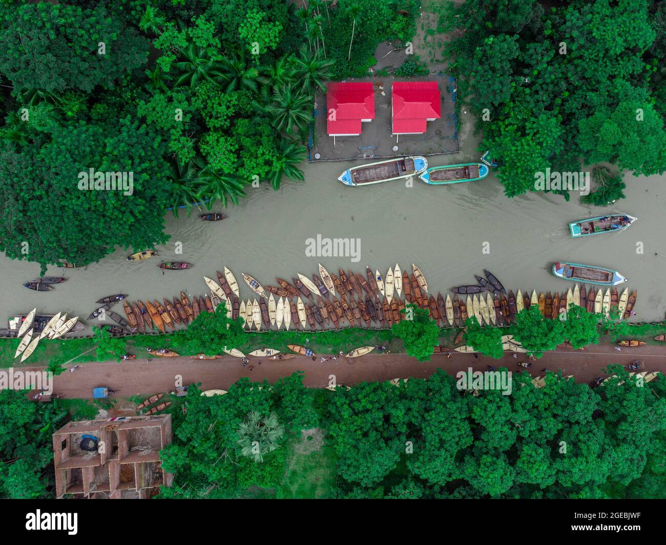 Barishal, Bangladesh, August 18, 2021: Aerial view of the Boat makers manufacture wood Boats  at   “Noukar Haat” (boat market) in Kuriana under the Swarupkathi upazila of Pirojpur district.  The Marketplace of Noukar Haat with a length of  two-kilometre-long  is noted for the trade in different varieties of boats during the monsoon season. The market runs every Friday from May to November. “Panis” or “Pinis”, “Dingi” and “Naak Golui” are the types of boats available for sale, built by local craftsmen from the Muktahar, Chami, Boldia, Inderhaat, Boitha Kata, Dubi and Kathali villages. Credit: M Stock Photo