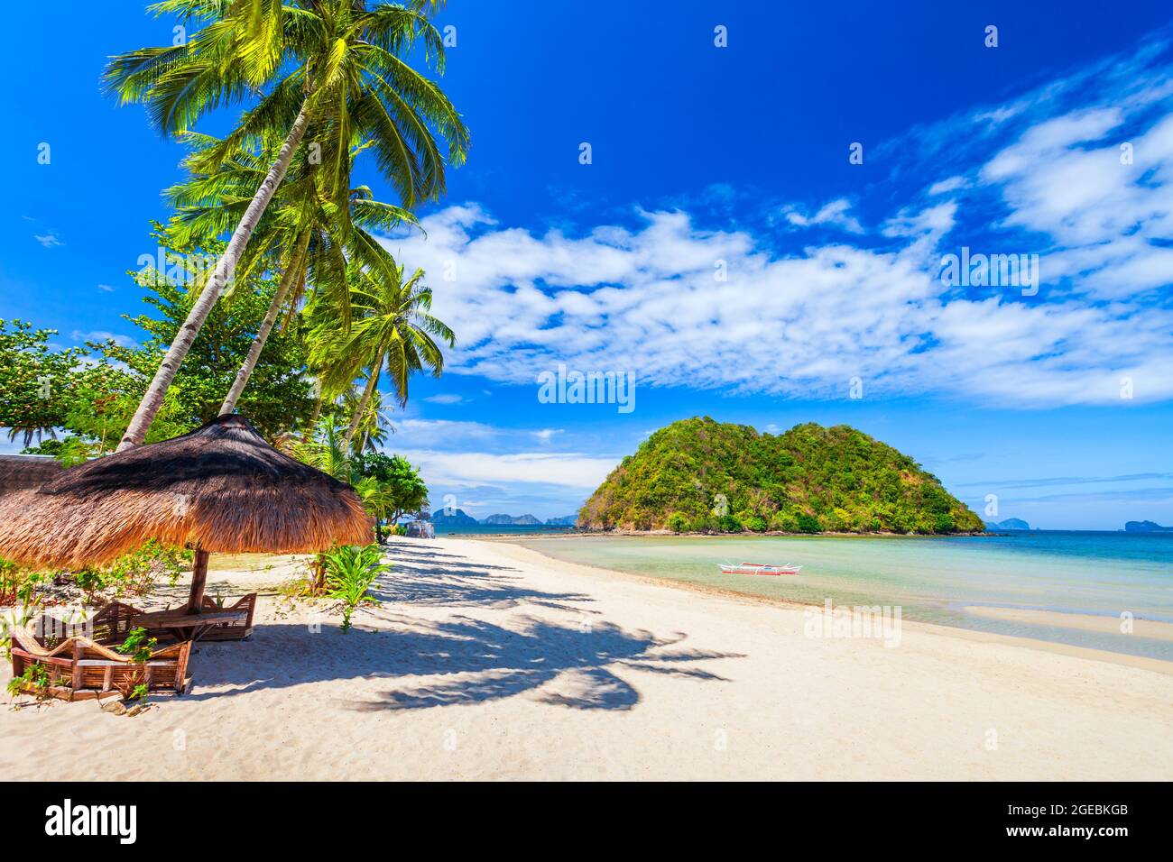 Beach with white sand, coconut palms and turquoise water in El Nido province, Palawan island in