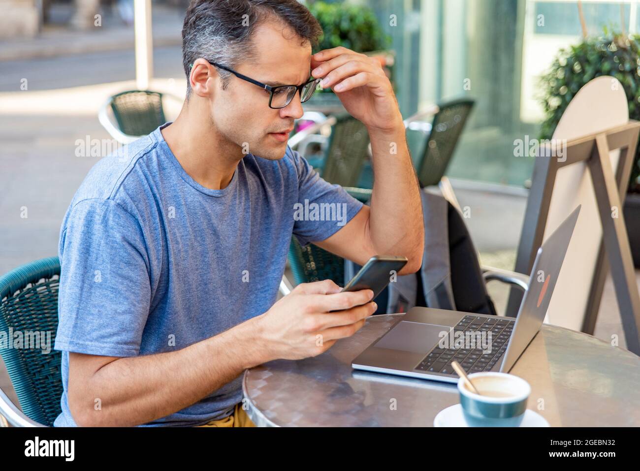 Young latin man stressed working with mobile phone and computer outside. Stock Photo
