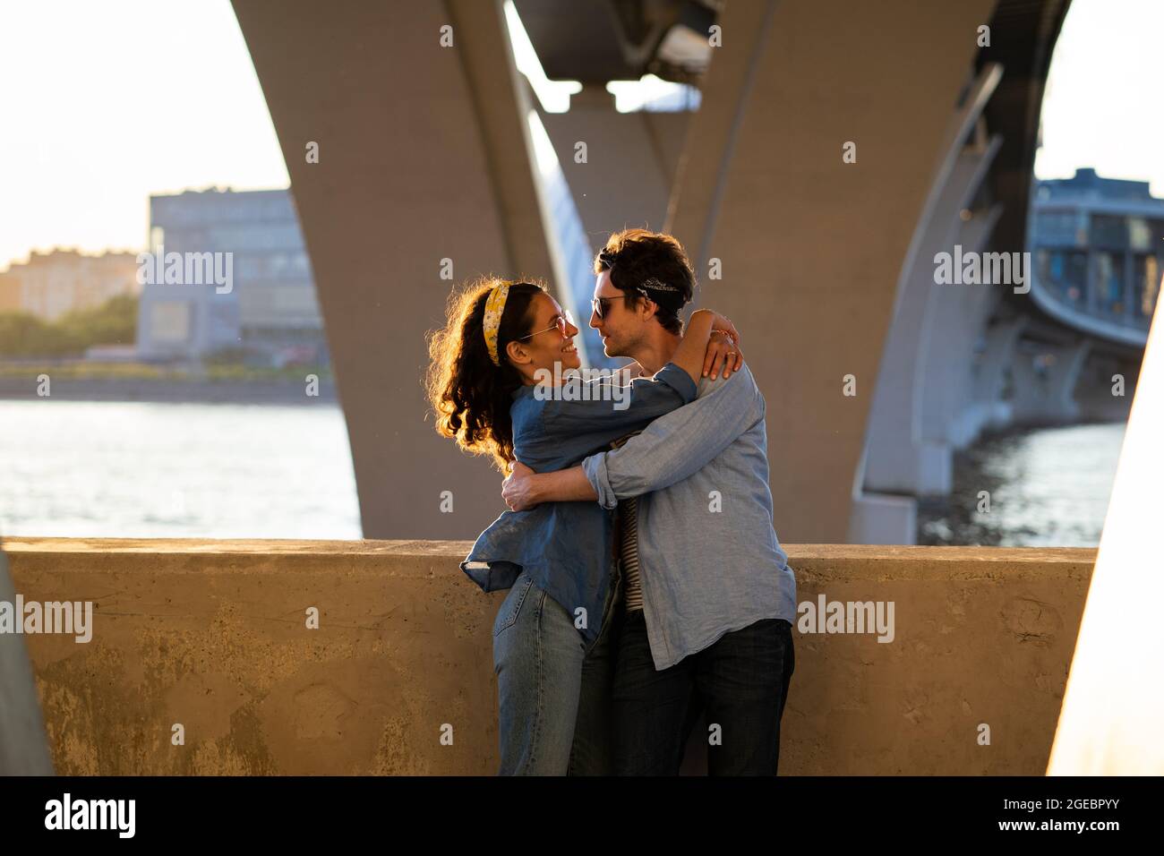 Couple in love at sunset hugging cuddling. Young adult man and woman in dating romantic relationship Stock Photo