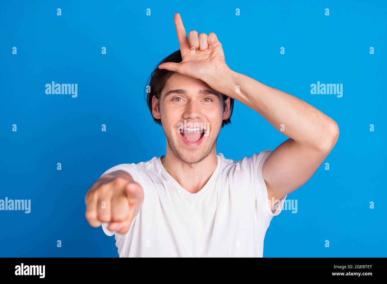 Photo of young happy cheerful man point finger you loser teaser funny funky  isolated on blue color background Stock Photo - Alamy