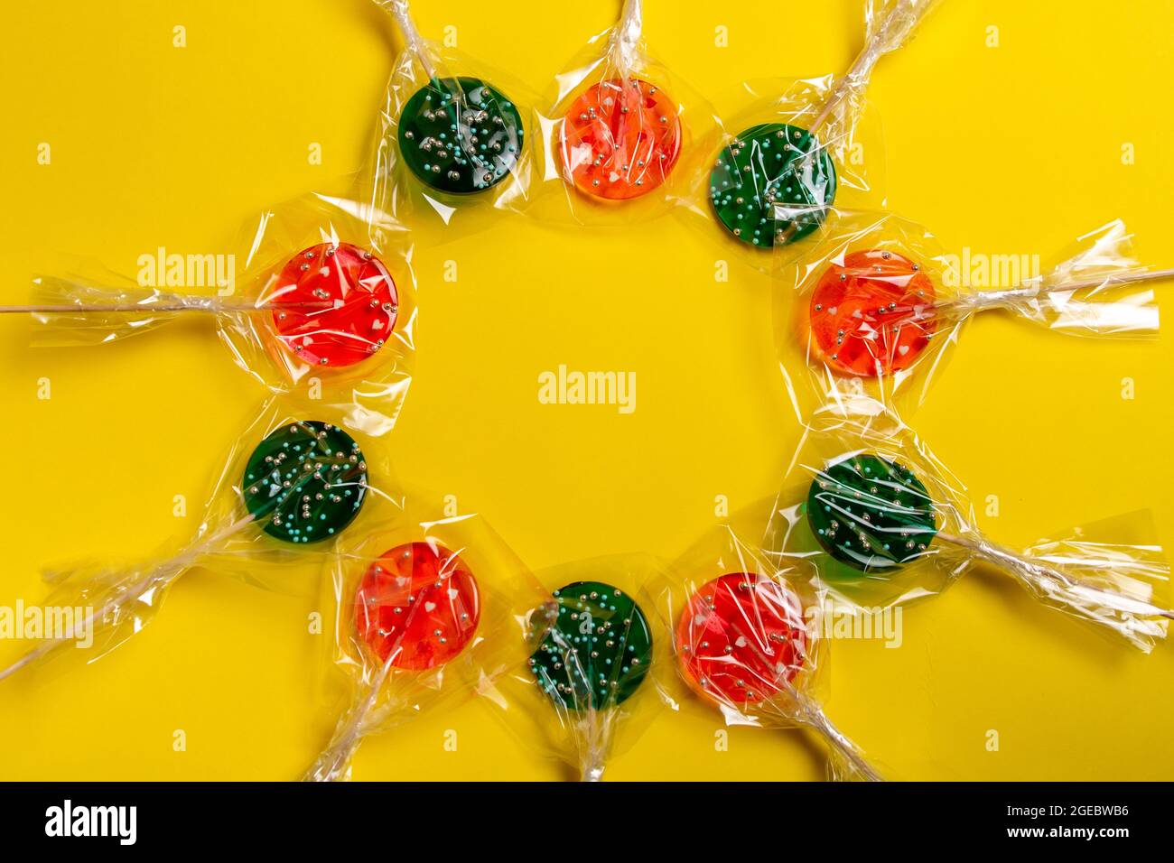 multi-colored lollipops on a stick on a yellow background. Stock Photo