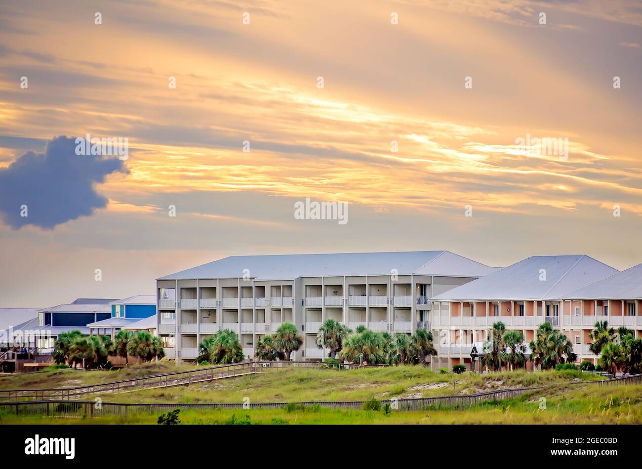 The sun sets behind condominiums on Dauphin Island’s west end, Aug. 12, 2021, in Dauphin Island, Alabama.The island is vulnerable to climate change. Stock Photo