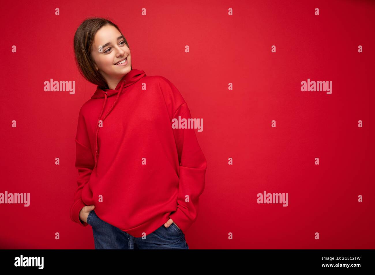 Photo Shot Of Pretty Positive Smiling Brunette Little Girl Wearing Stylish Red Hoodie Standing Isolated Over Red Background Wall Looking To The Side Stock Photo Alamy