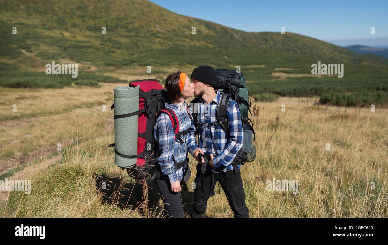 couple in love tourists man and woman stand on a mountain plain kissing passionately. Hiking concept. copy space Stock Photo