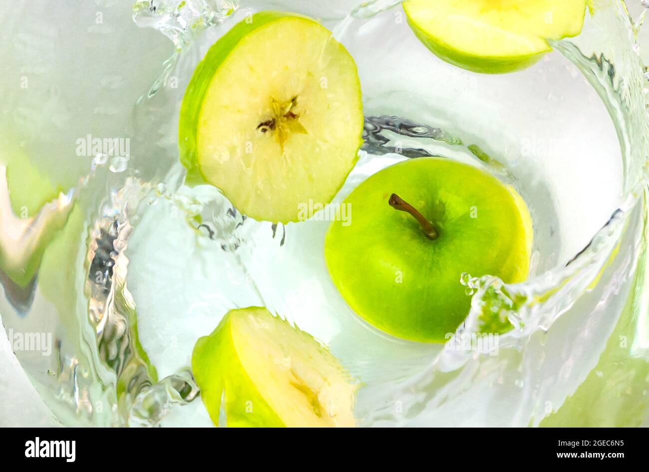 Close up green apples falling in water with splash. Stock Photo