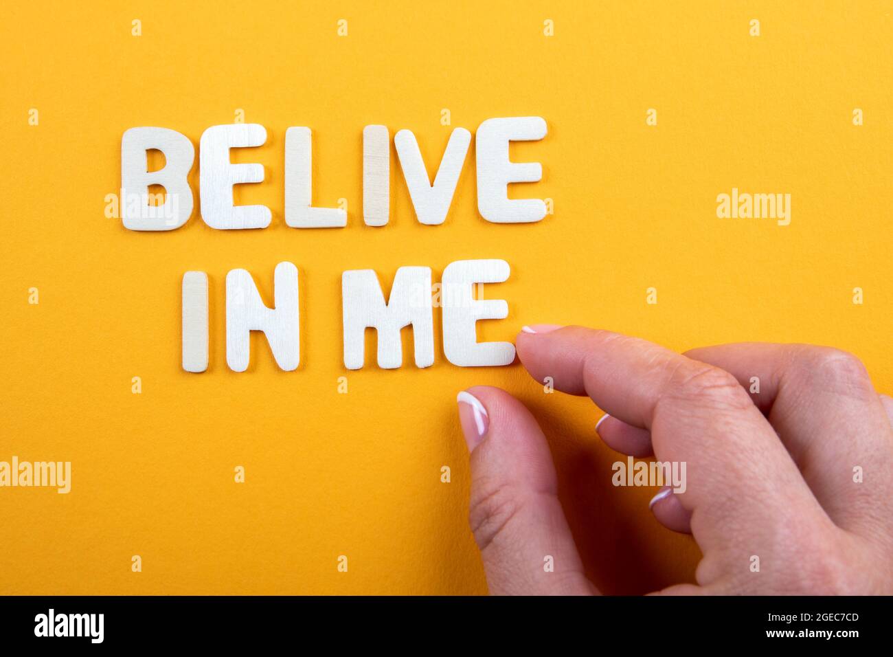 Belive In Me. White wooden letters with text on a yellow background. Stock Photo