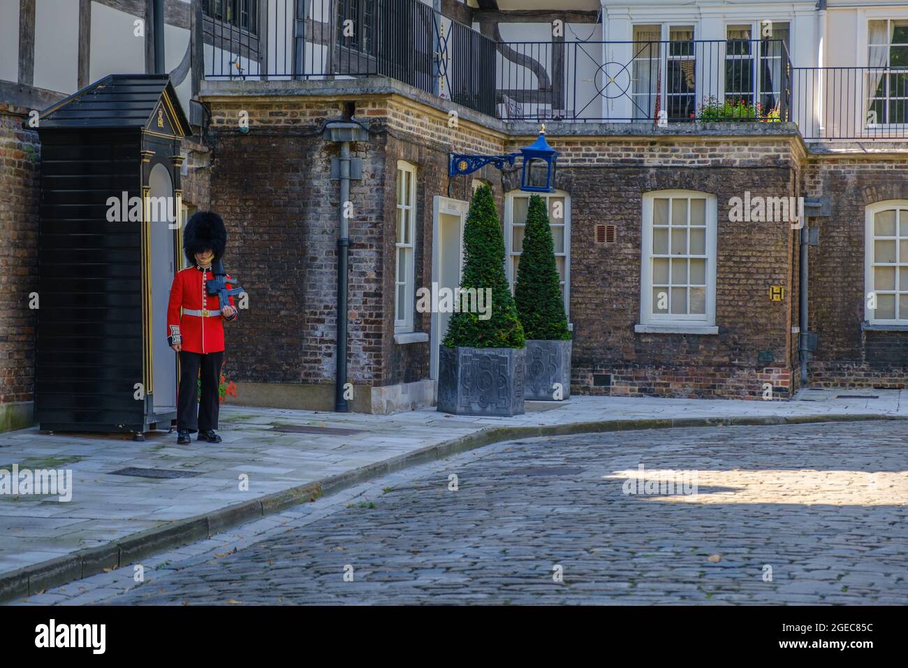 Staycation idea. Coldstream Guards sentry in military dress holding a gun posted at sentry box in front of the Queen's House at the Tower of London. Stock Photo