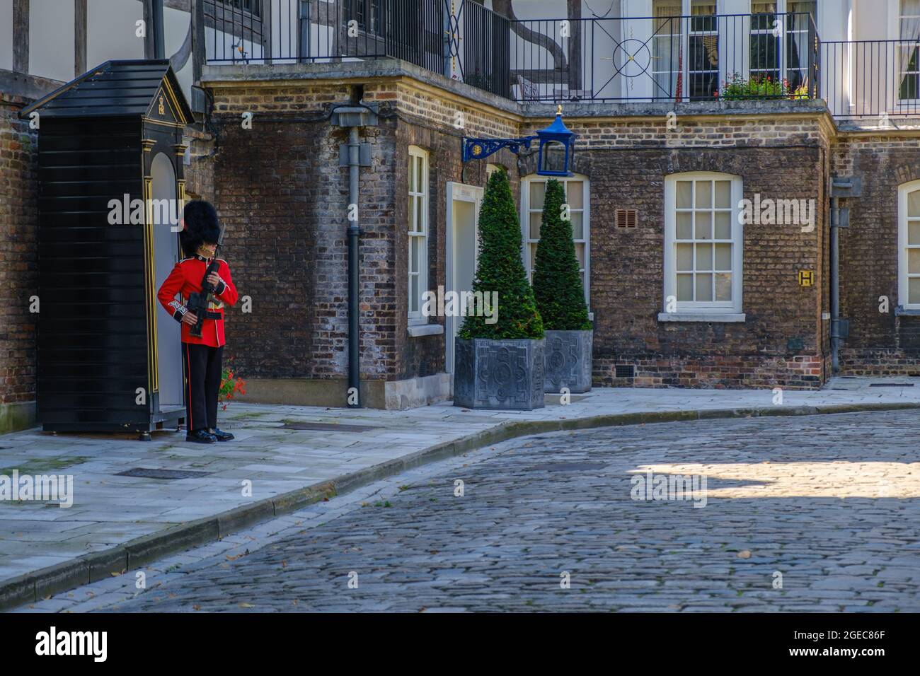 Staycation idea. Coldstream Guards sentry in military dress holding a gun posted at sentry box in front of the Queen's House at the Tower of London UK Stock Photo