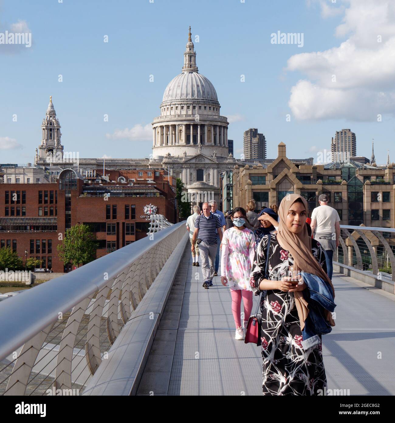 London, Greater London, England, August 10 2021: People of different ethnicities walking on Millennium Bridge with St Pauls Cathedral behind. Stock Photo
