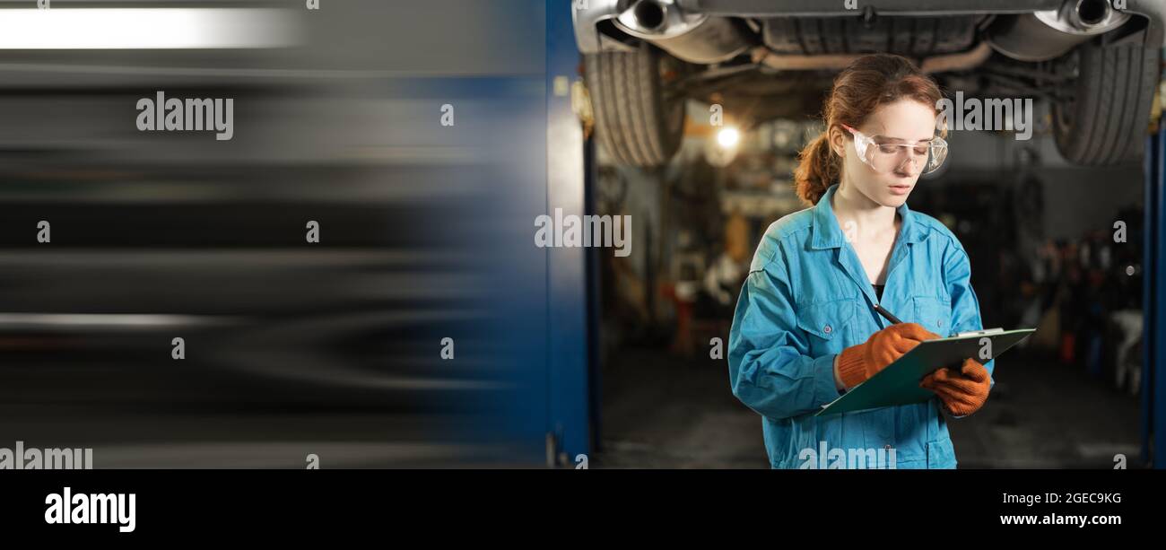 A woman mechanic stands against the background of a raised car. holds the tablet in his hands and records the damage. Marks with a pen. Copy space. 4k Stock Photo