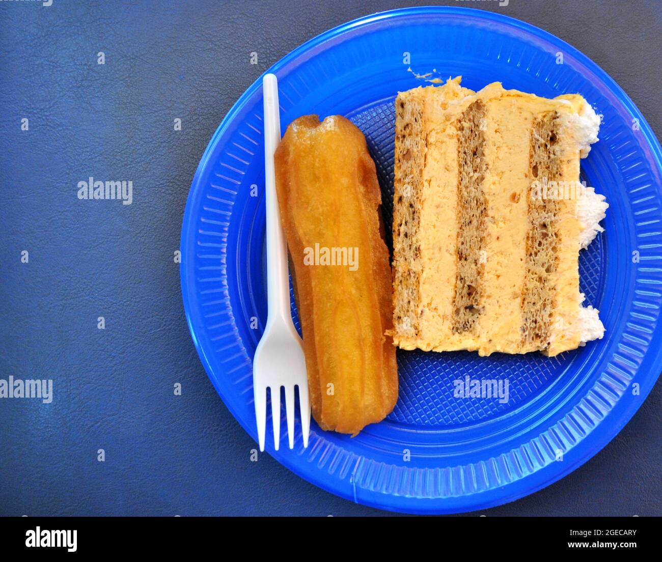 cake and turkuish sweet Tulumba dessert in a blue disposable plate top view.eastern an western cullture concept Stock Photo