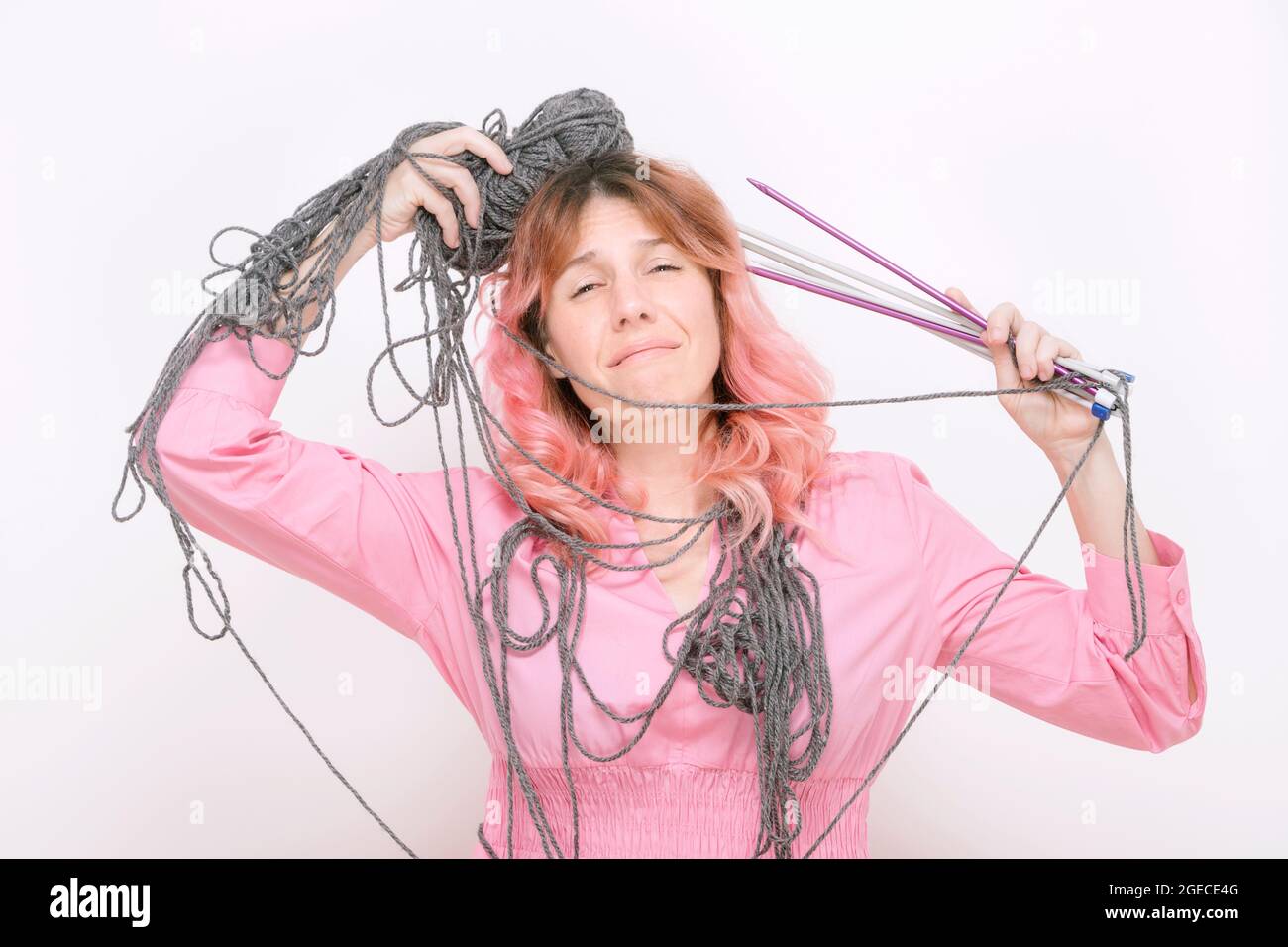 stressed woman with wool and knitting needles entangled in her body Stock Photo