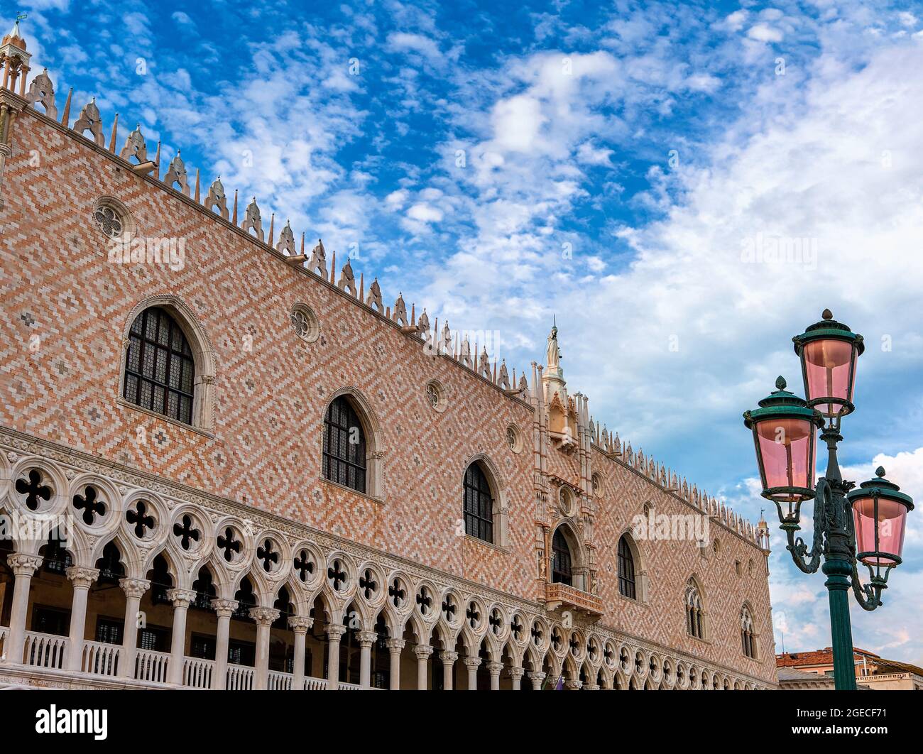 Venetian Doge's palace or Palazzo Ducale in Venice, Italy. Beautiful view of pink wall and arcade and clouds in blue sky. UNESCO World heritage city Stock Photo