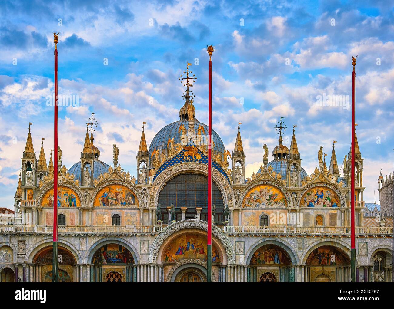 Main facade of St Mark's cathedral, Venice. Italy. UNESCO World Heritage city, blue sky and clouds. Decorations, mosaics, marble carvings, statues. Stock Photo