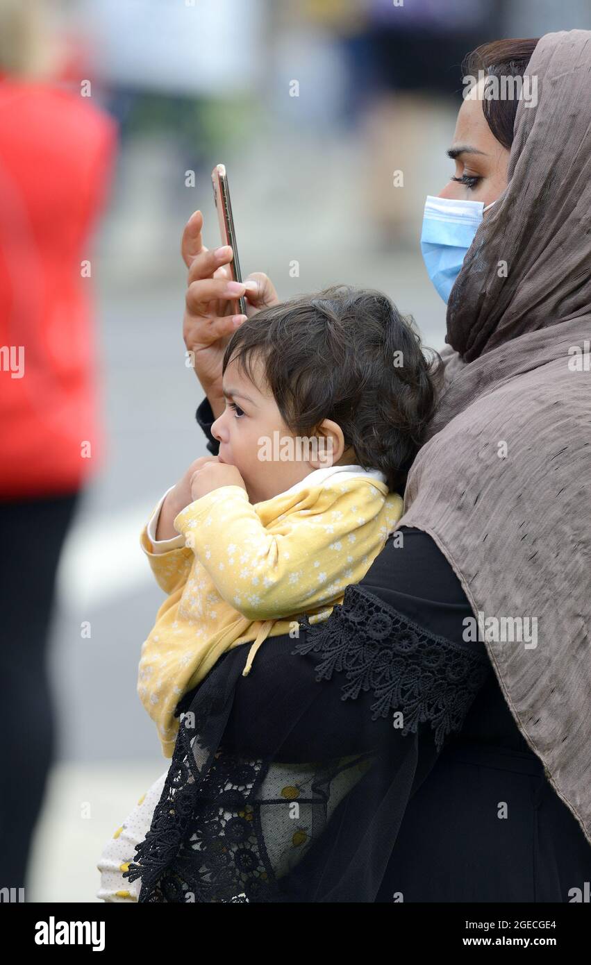 London, England, UK. Afghan woman with her young child, on her mobile phone, in Westminster as the Taliban takeover of Afghanistan is discussed in Par Stock Photo