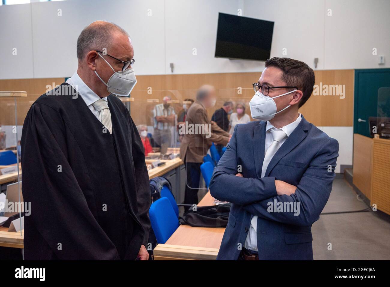 Trier, Germany. 19th Aug, 2021. Senior public prosecutor Eric Samel (r) talks to lawyer Frank Peter, counsel for the defendant, before the trial in the courtroom of Trier Regional Court. The defendant is alleged to have raced through Trier's pedestrian zone in his SUV on December 1, 2020, with the aim of killing or injuring as many people as possible. The prosecution accuses him of five counts of murder and 18 counts of attempted murder. Credit: Harald Tittel/dpa - ATTENTION: Person in background pixelated by order of the court/dpa/Alamy Live News Stock Photo