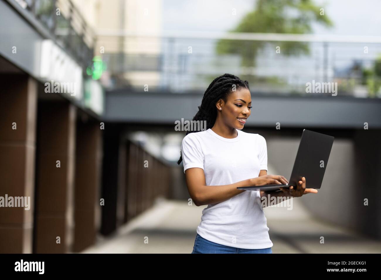 Beautiful African woman with laptop while happily looking in camera ...