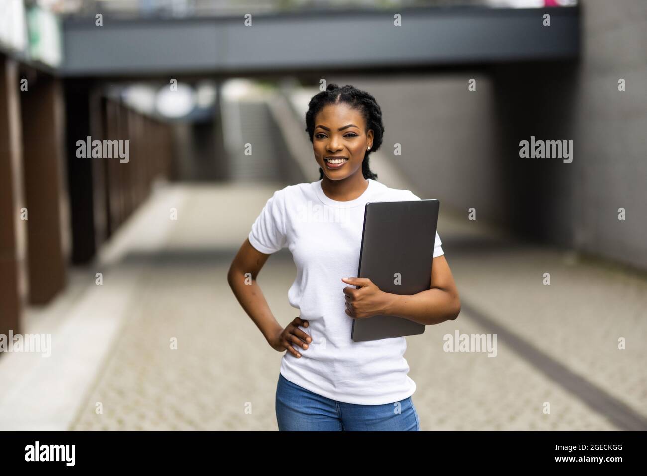 Beautiful African woman with laptop while happily looking in camera ...