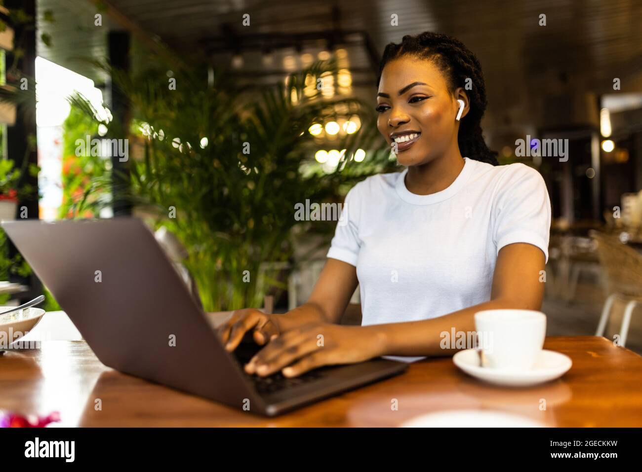 Happy black girl in wireless headphones studying online, using laptop ...