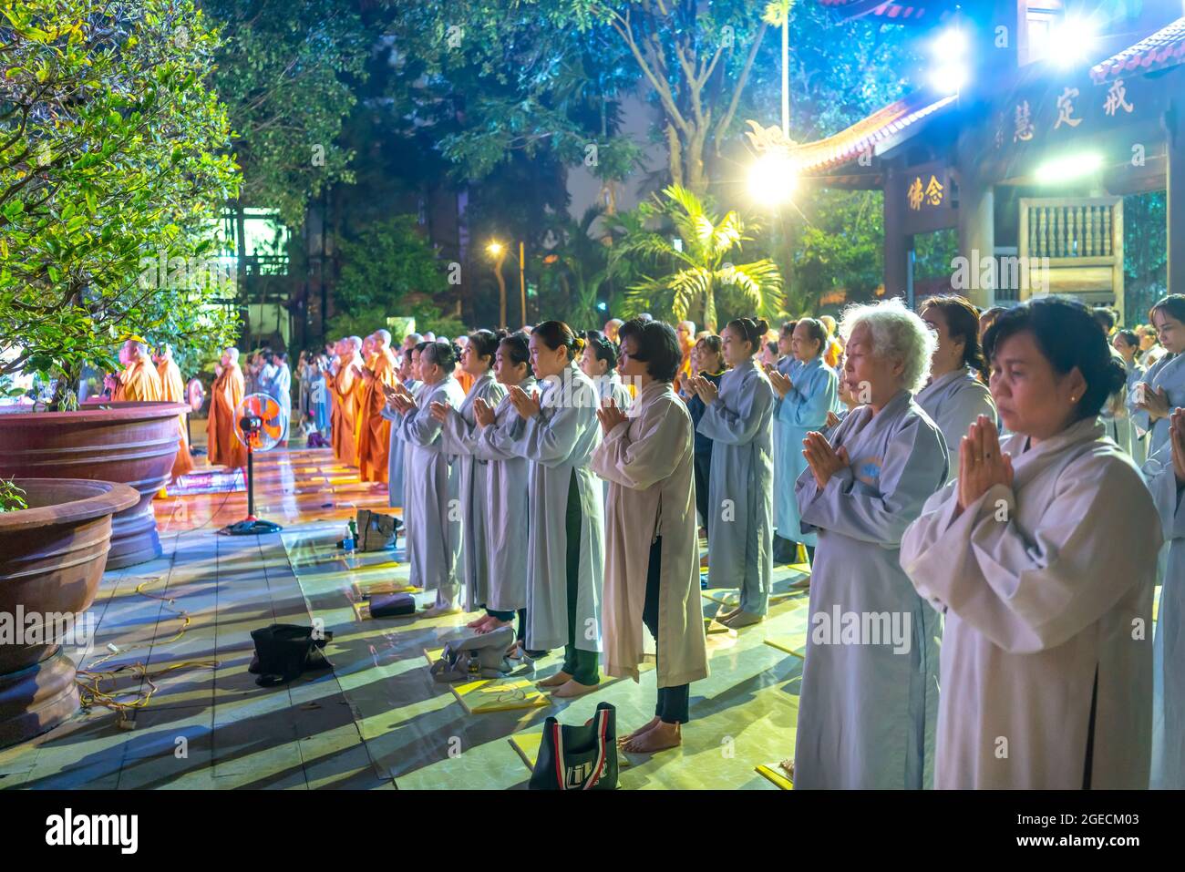 Monks and Buddhists are reverently bowing to Buddha during evening ceremony for Amitabha Buddha at an ancient temple in Ho Chi Minh City, Vietnam Stock Photo