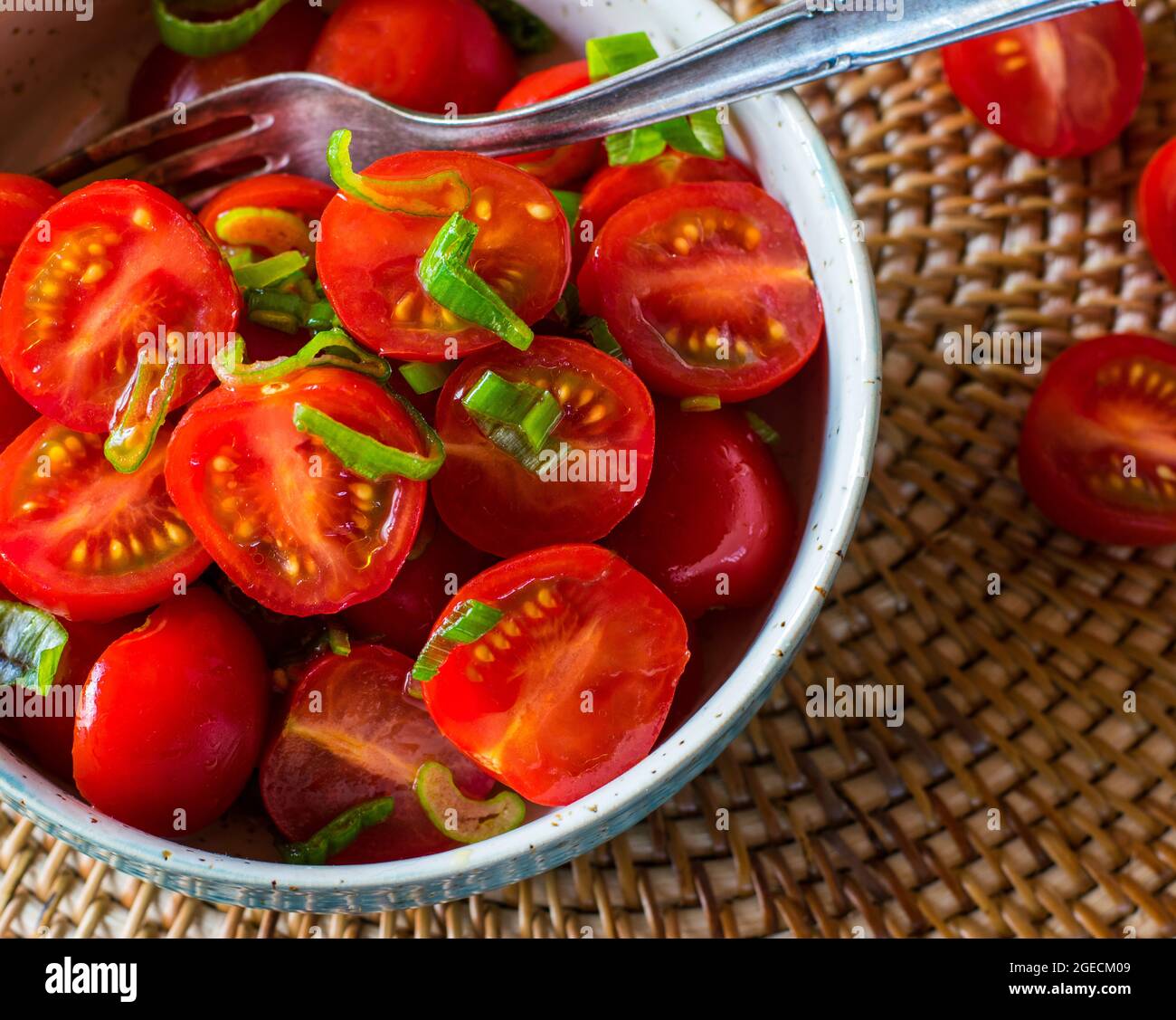 A bowl of fresh cherry tomatoes with olive oil and chives Stock Photo
