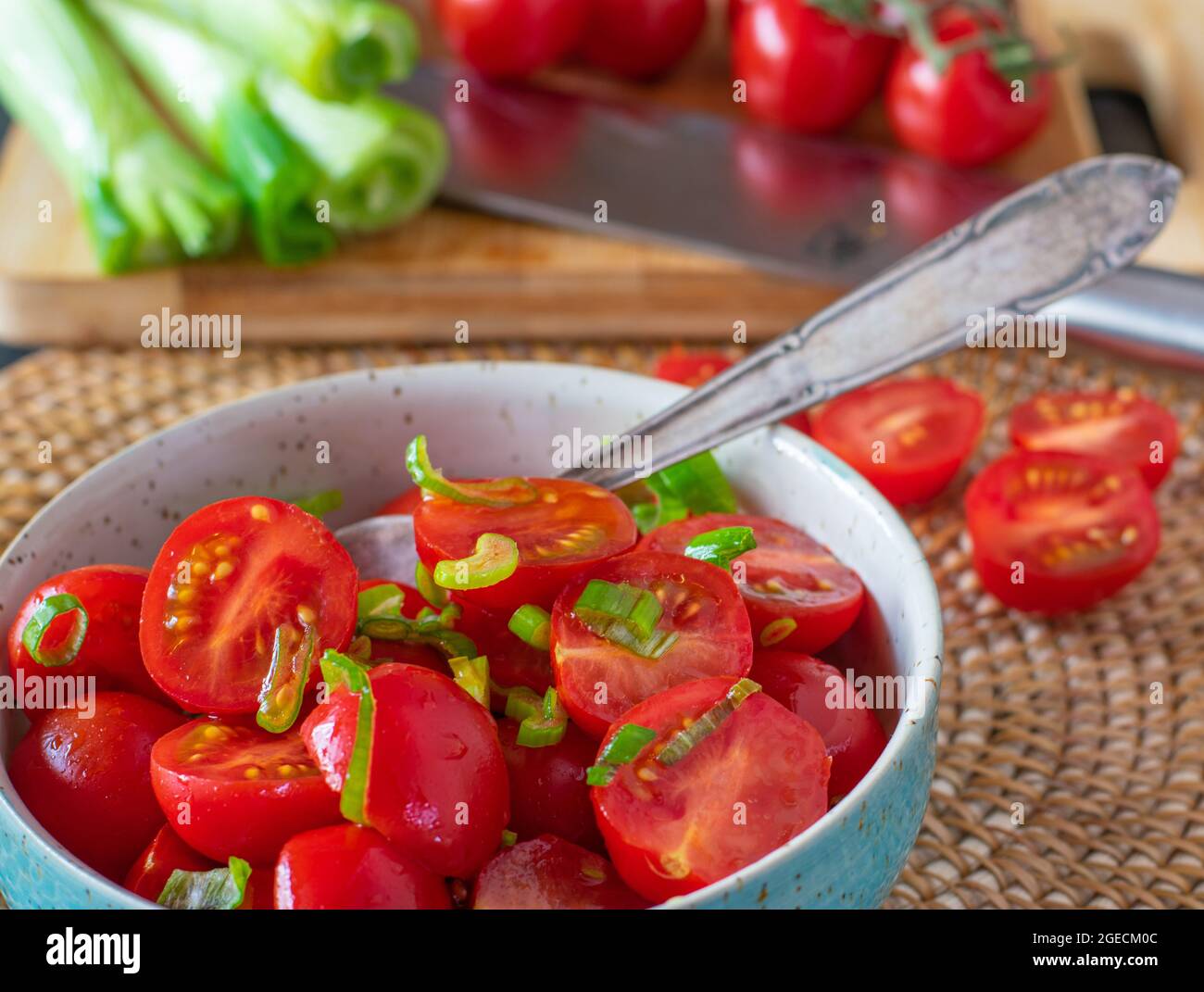 A bowl of fresh cherry tomatoes with olive oil and chives Stock Photo