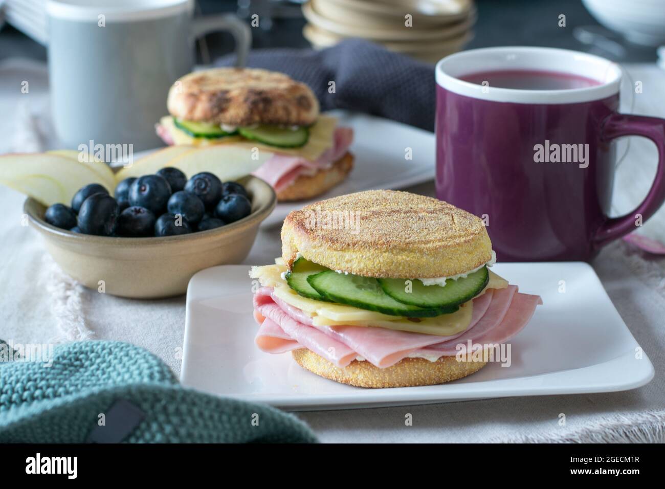Healthy breakfast sandwich made with toasted english muffin topped with ham, cheese and cucumber