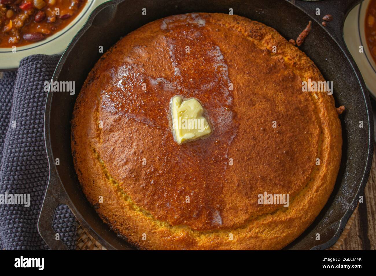 homemade fresh baked cornbread in a rustic cast iron pan topped with melted butter Stock Photo