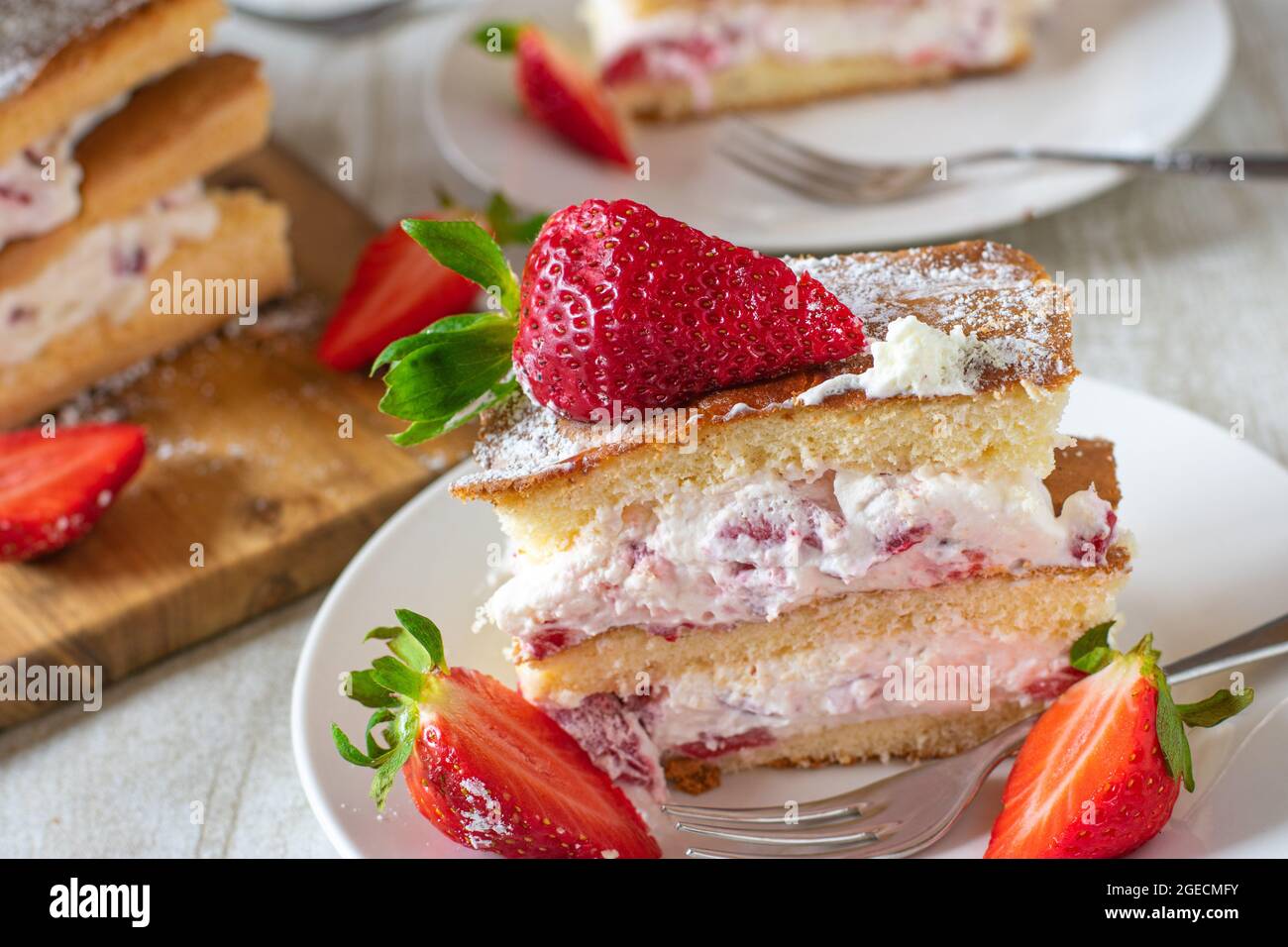Homemade strawberry cream cake on rustic table background Stock Photo