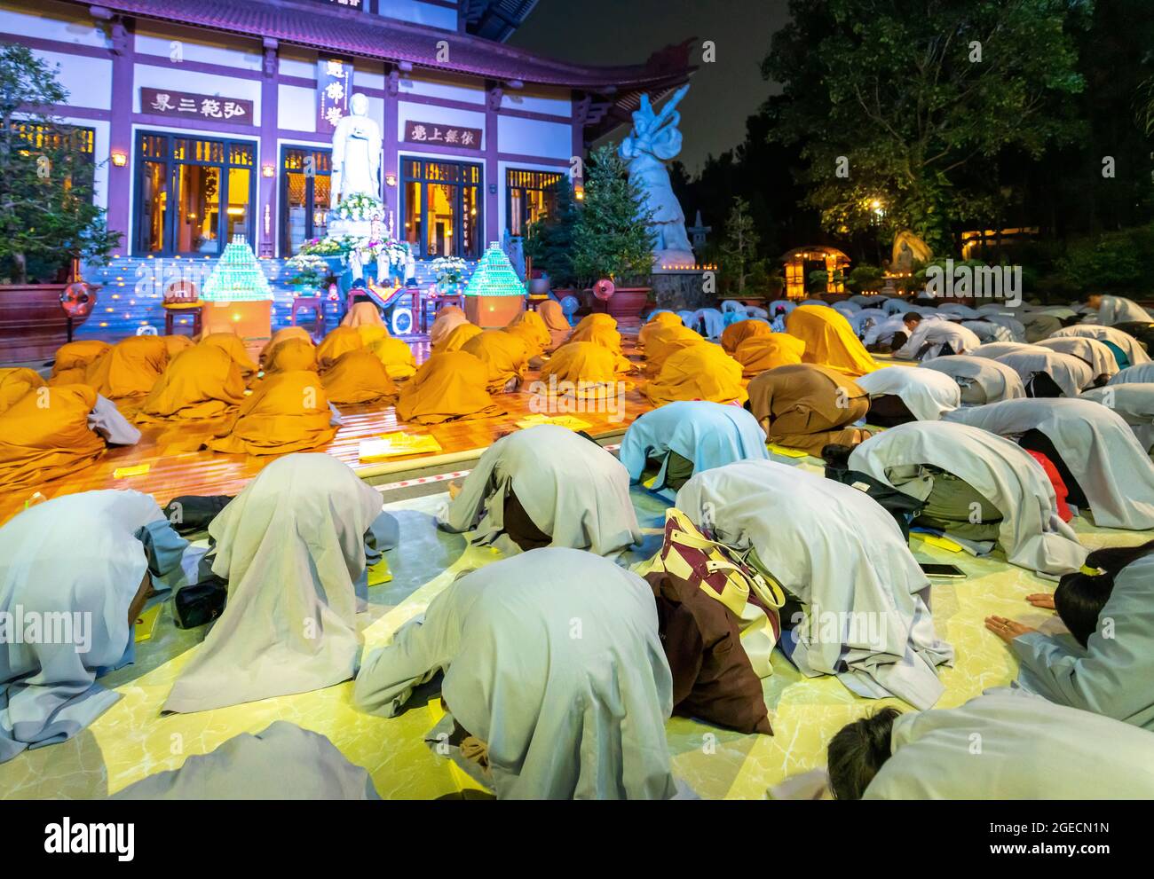 Monks are reverently bowing to Buddha during evening ceremony for Amitabha Buddha at an ancient temple in Ho Chi Minh City, Vietnam Stock Photo