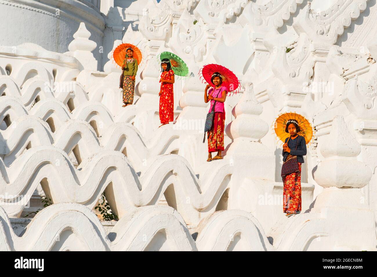 Local female worshipers with parasols ascending the hsinbyume pagoda, Mingun, Myanmar Stock Photo
